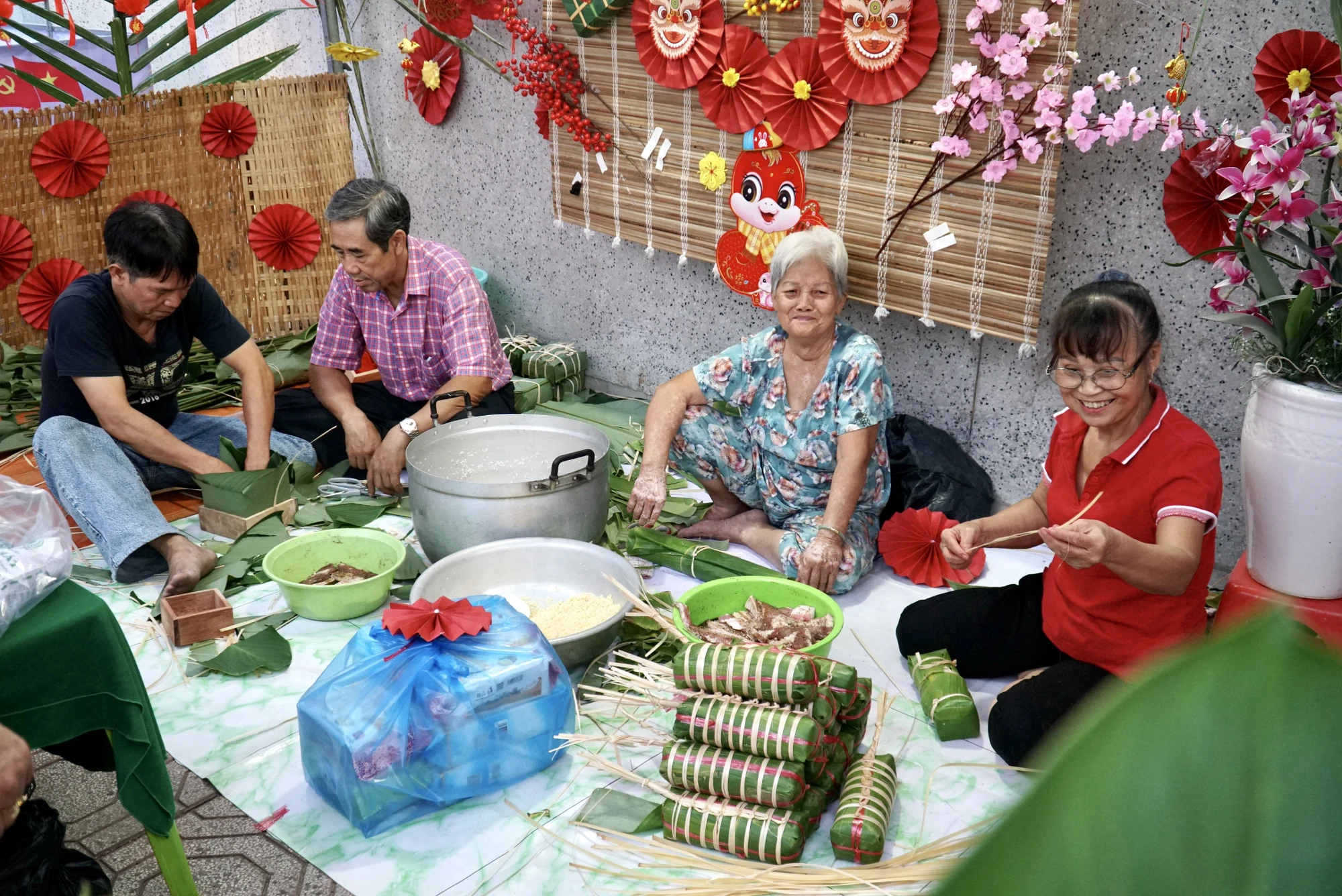 Người dân phường Tân Thuận Tây cùng gói bánh tét trong ngày hội “Xuân đoàn kết - Tết nghĩa tình”. Ảnh: BẢO PHƯƠNG Tết nghĩa tình