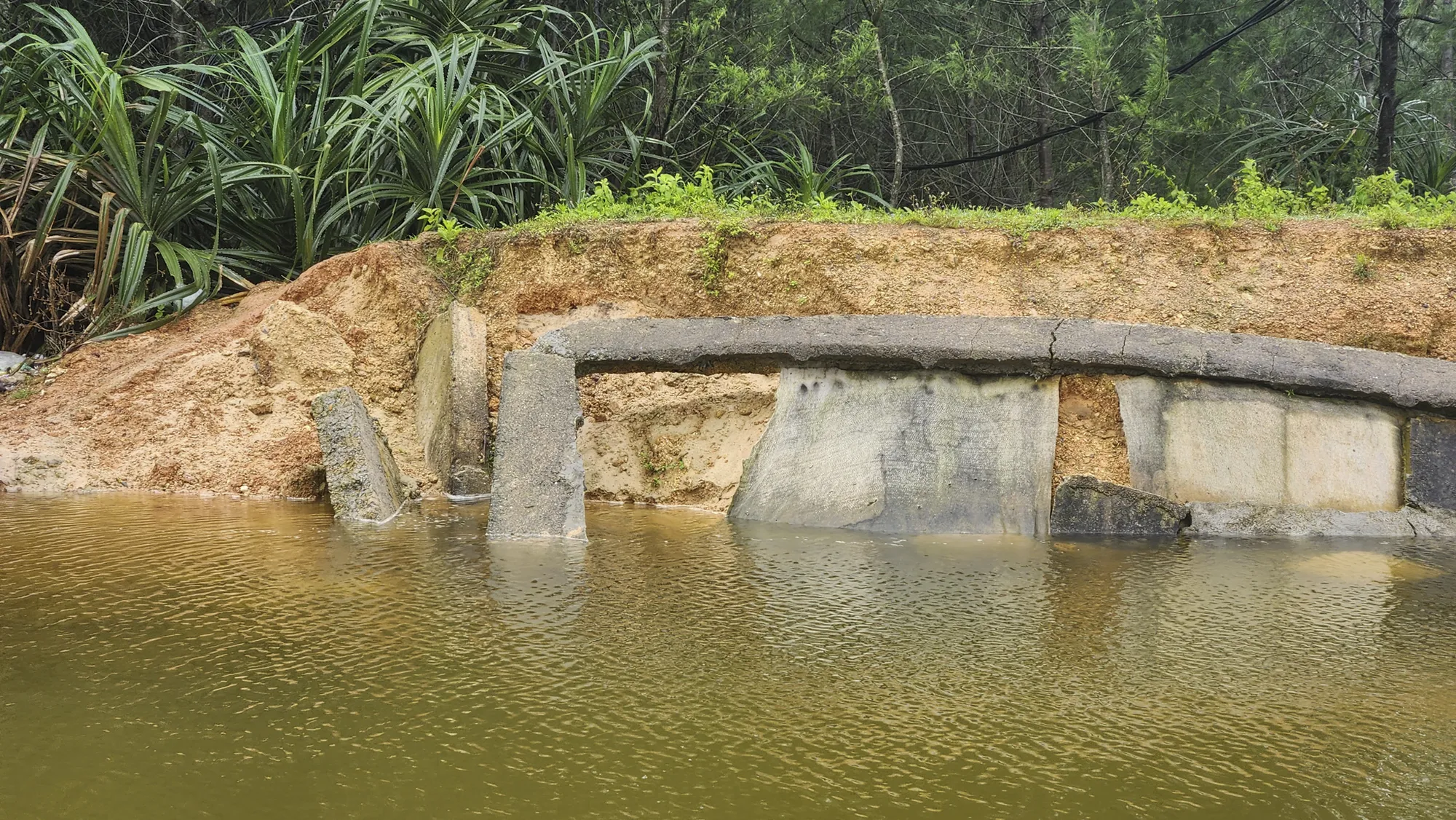 Đại diện công ty TNHH Hải Triều cho biết, theo thiết kế thì bờ kè này không được trải bê tông dưới lòng kênh nên khi nước chạy xiết gây xói lở dưới chân bờ kè dẫn đến việc bị sụt lún, hư hỏng. bo-ke-sat-lo-21.jpg