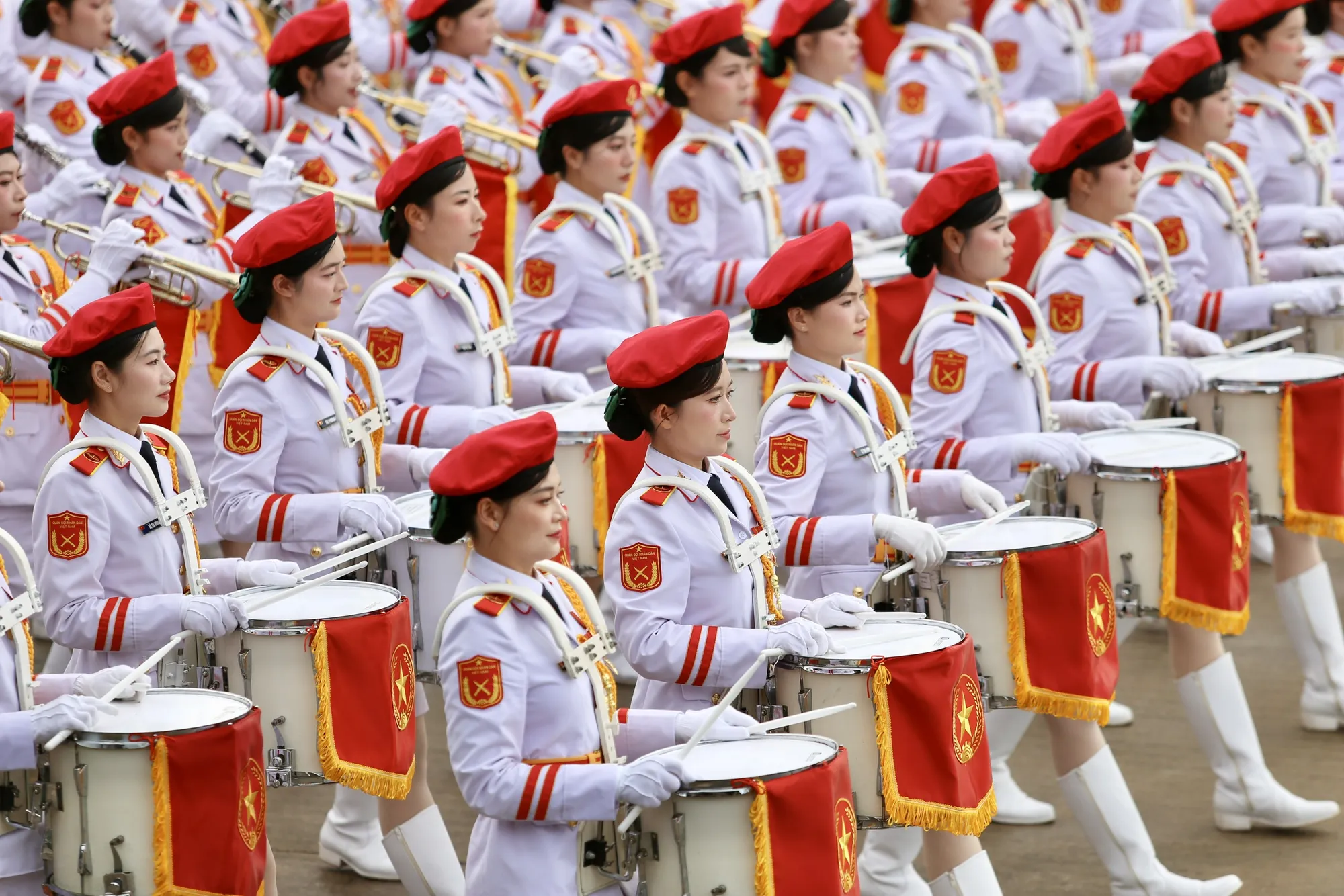 Giữa hàng ngũ chỉnh tề, Khối nữ quân nhạc trong quân phục trắng tinh, hàng trăm khuôn mặt sáng bừng dưới ánh nắng sớm, tay ôm kèn, trống... từng bước tiến ra sân tổng duyệt diễu binh, diễu hành . Tổng duyệt diễu binh A80 (19).jpg