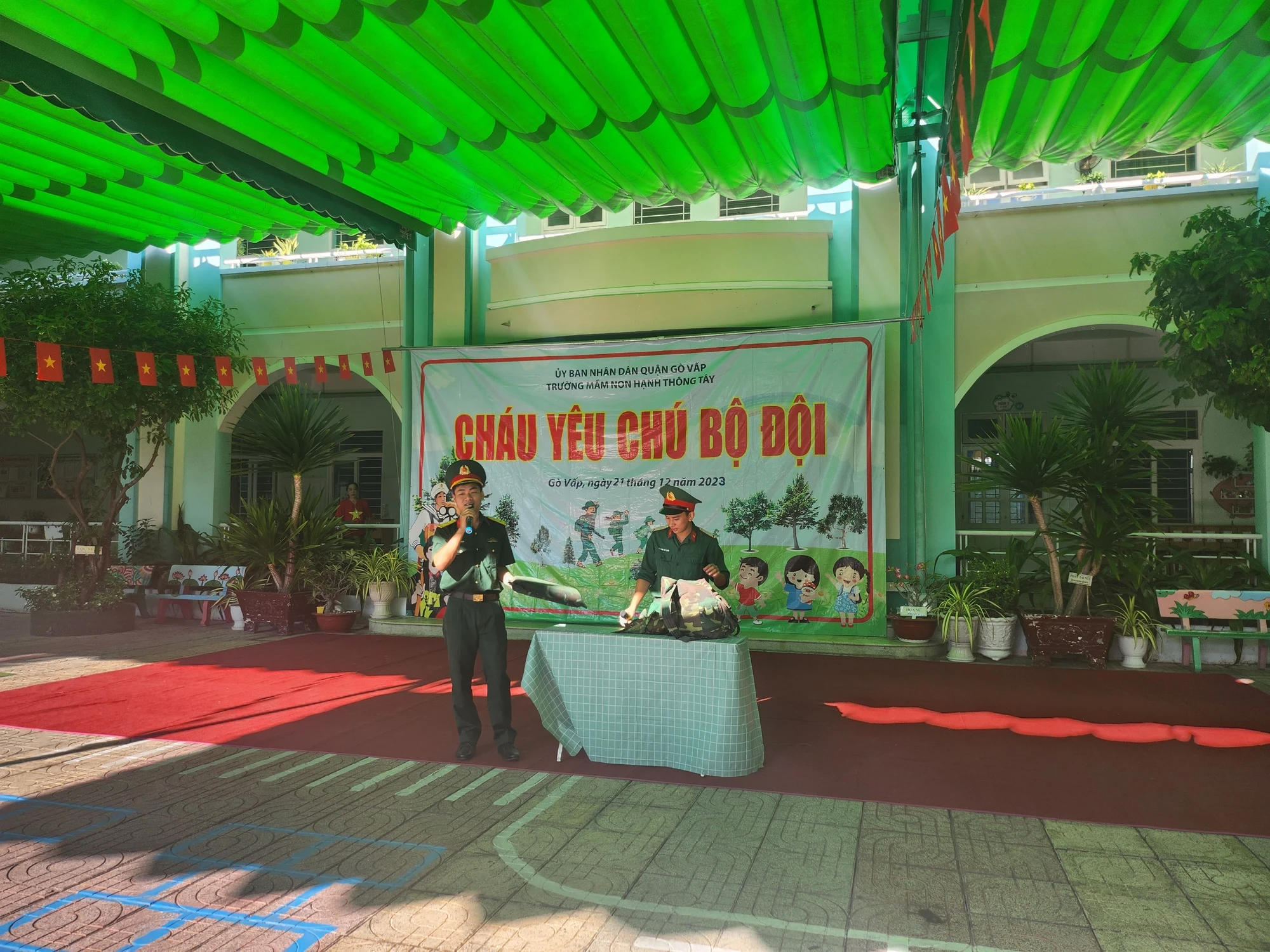 Chú bộ đội giới thiệu cho các bé về các vật dụng không thể thiếu của một người lính tại sân trường giao lưu với chú bộ đội