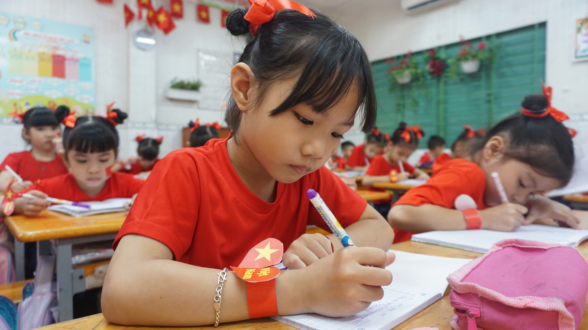 Ngoài áo cờ đỏ sao vàng, các em còn được cô giáo và phụ huynh chuẩn bị vòng đeo tay "Tôi yêu Việt Nam", hình dán trên mặt và những chiếc nơ buộc tóc màu đỏ. man-dong-dien-the-duc-10.JPG