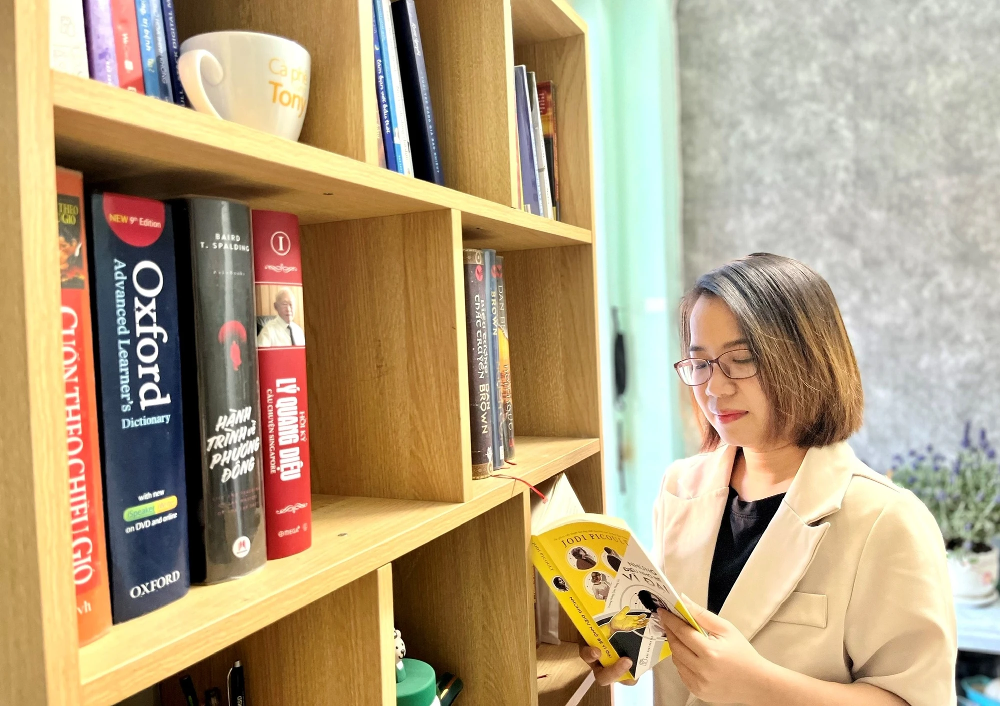 Tác giả bên kệ sách tự tay lắp ghép trong căn nhà trọ của mình. Ảnh: NVCC