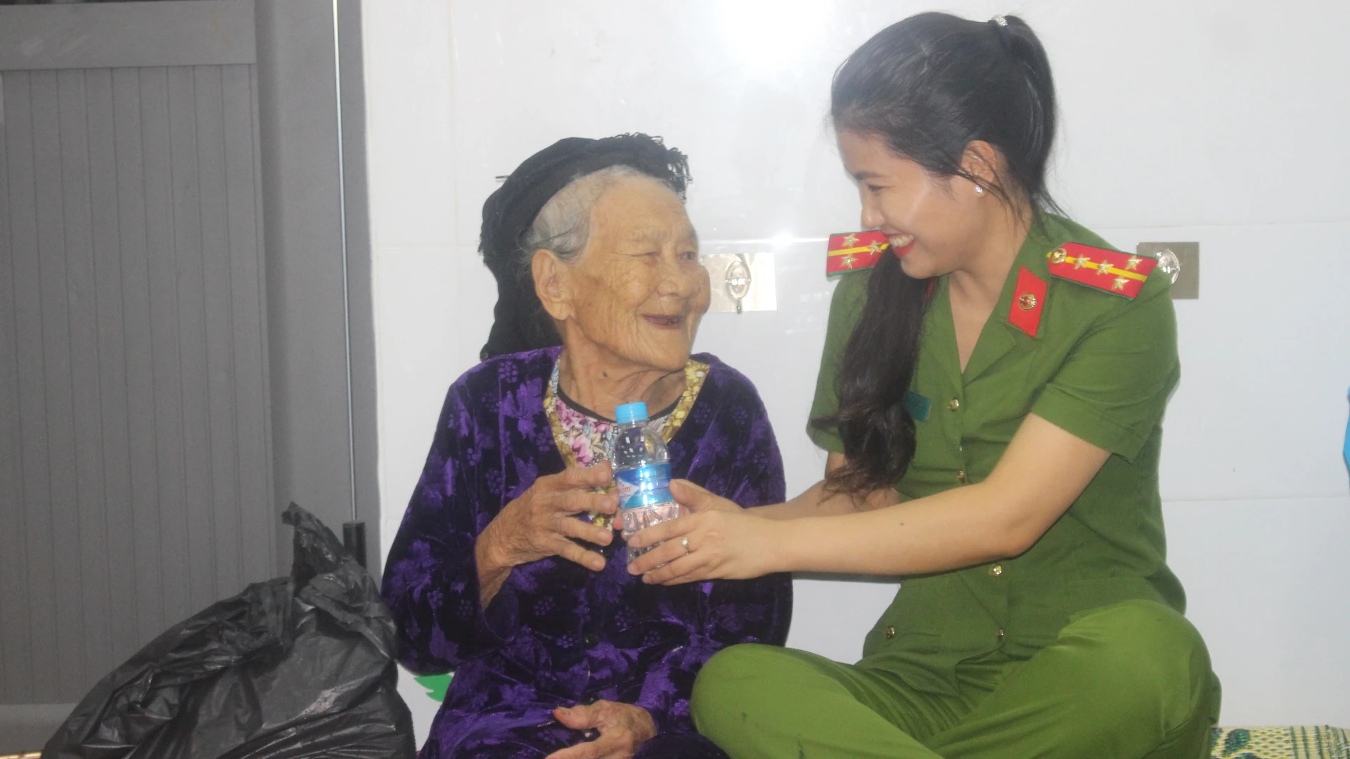 Nữ cán bộ Công an xã Nghi Xuân trò, chuyện, động viên, chăm sóc cụ bà Hồ Thị Ngoan.