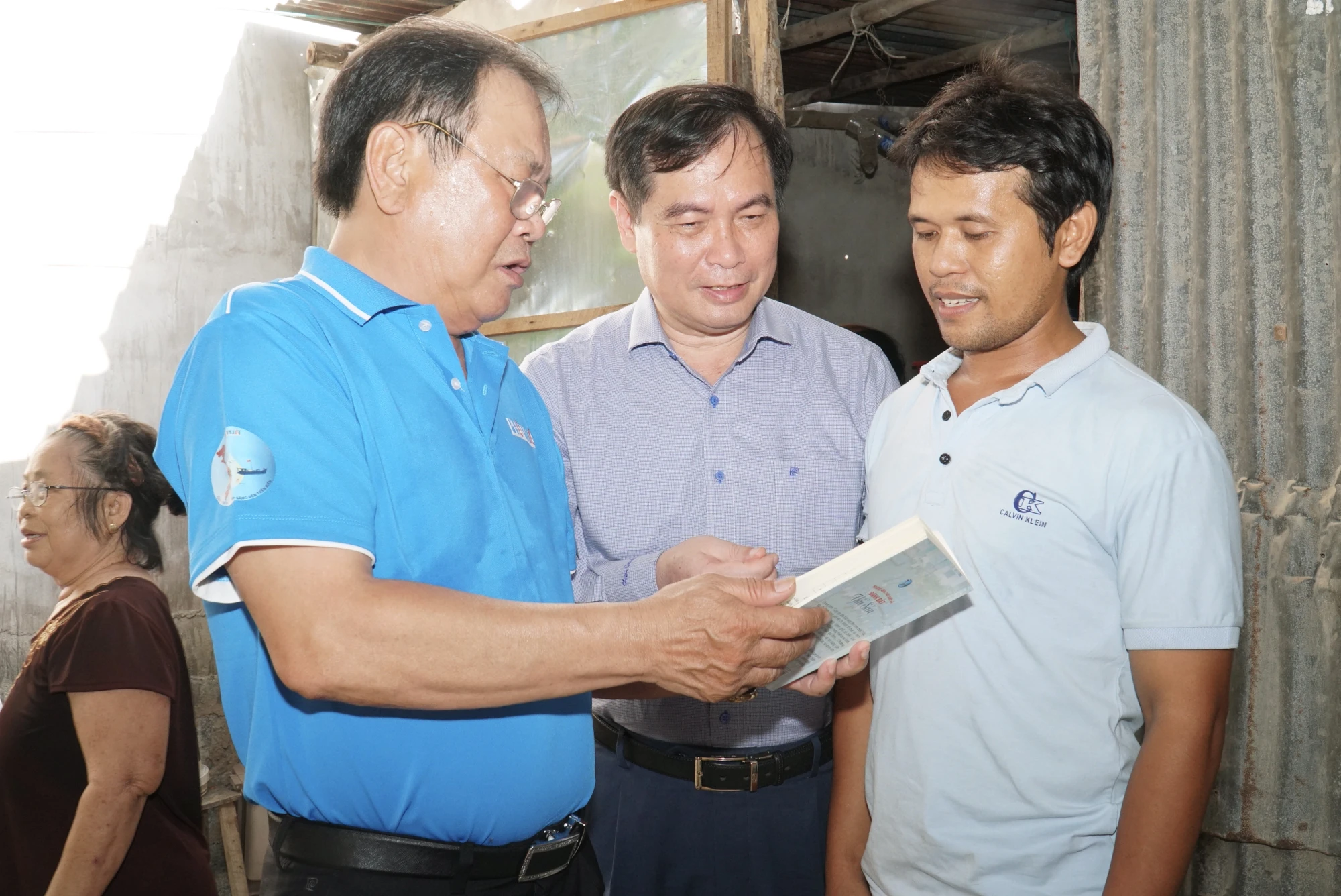 Ngư dân Nguyễn Văn Công (bìa phải, 36 tuổi, ngụ khu phố 9) cho biết đã gắn bó với nghề biển được 24 năm nay. Dù cuộc sống còn khó khăn nhưng chưa bao giờ anh Công có suy nghĩ sẽ từ bỏ nghề biển. Mong mỏi lớn nhất của anh Công bây giờ là mùa màng bội thu, để anh an tâm ra khơi đánh bắt, cải thiện thu nhập gia đình. Trong ảnh: Phó Trưởng Ban Tuyên giáo Trung ương Phan Xuân Thủy (giữa) cùng Tổng biên tập báo Pháp Luật TP.HCM Mai Ngọc Phước thăm hỏi ngư dân Nguyễn Văn Công và giới thiệu nội dung cuốn cẩm nang "Những điều cần biết khi đánh bắt hải sản". Ảnh: BẢO PHƯƠNG