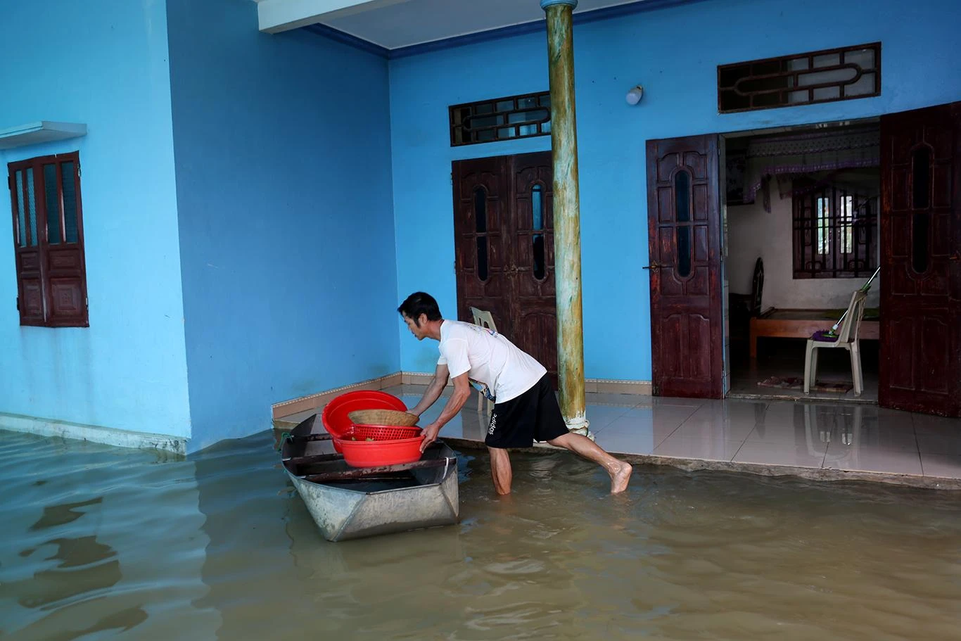 Một người đàn ông ở thôn kén đưa các tài sản còn lại là rổ giá lên tầng 2, vì khả năng trong đêm nước lũ đổ về tiếp tục dâng cao. Ảnh: ĐẶNG TRUNG