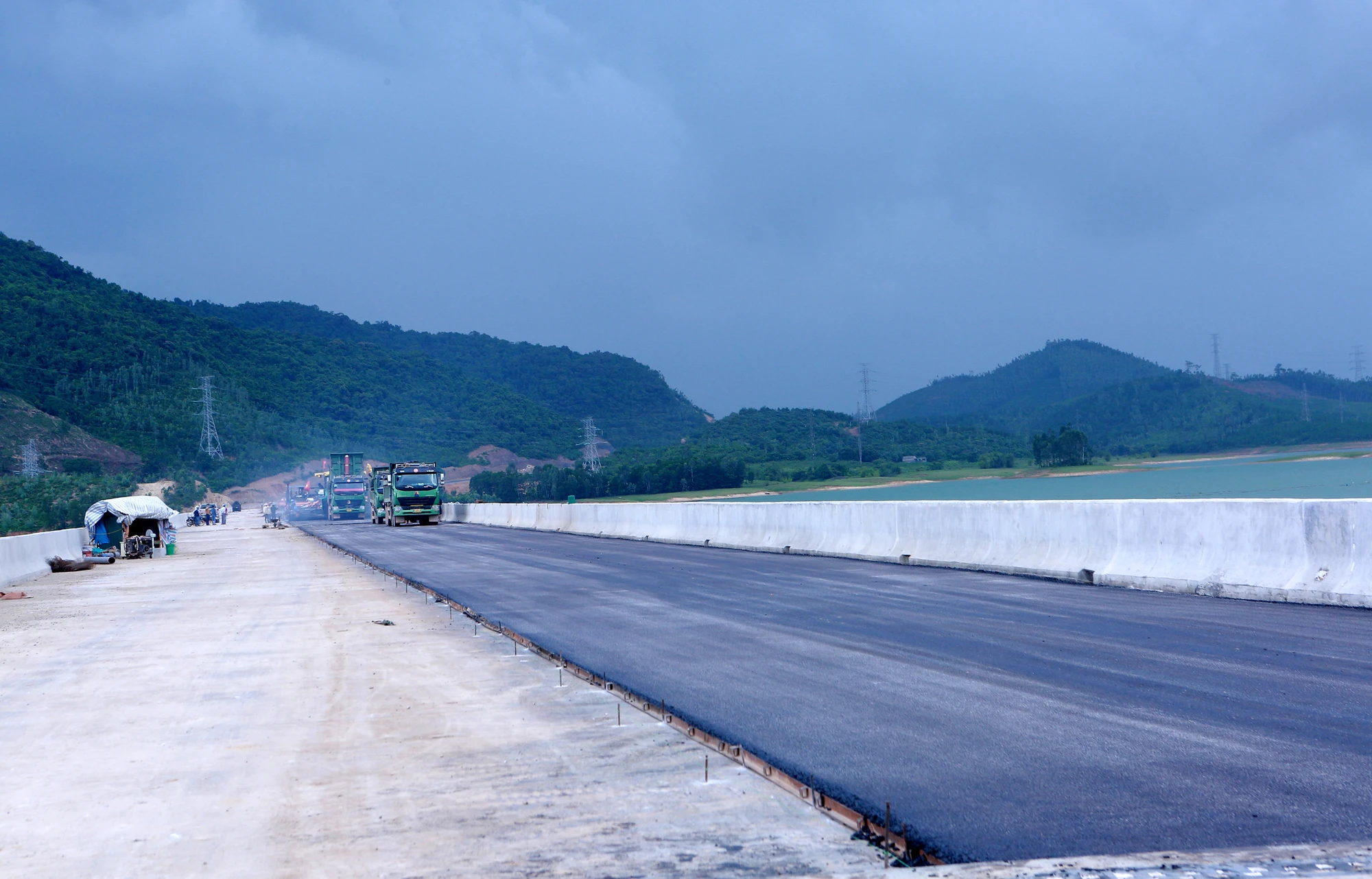 Công nhân, máy móc phương tiện được huy động tối đa để tiến hành hành thảm nhựa, cùng với đó là tiến hành lắp đặt các hệ thống điện, lan can cầu, biển báo cũng đang được được triển khai đảm bảo tiến độ kịp thông xe. Ảnh: ĐẶNG TRUNG