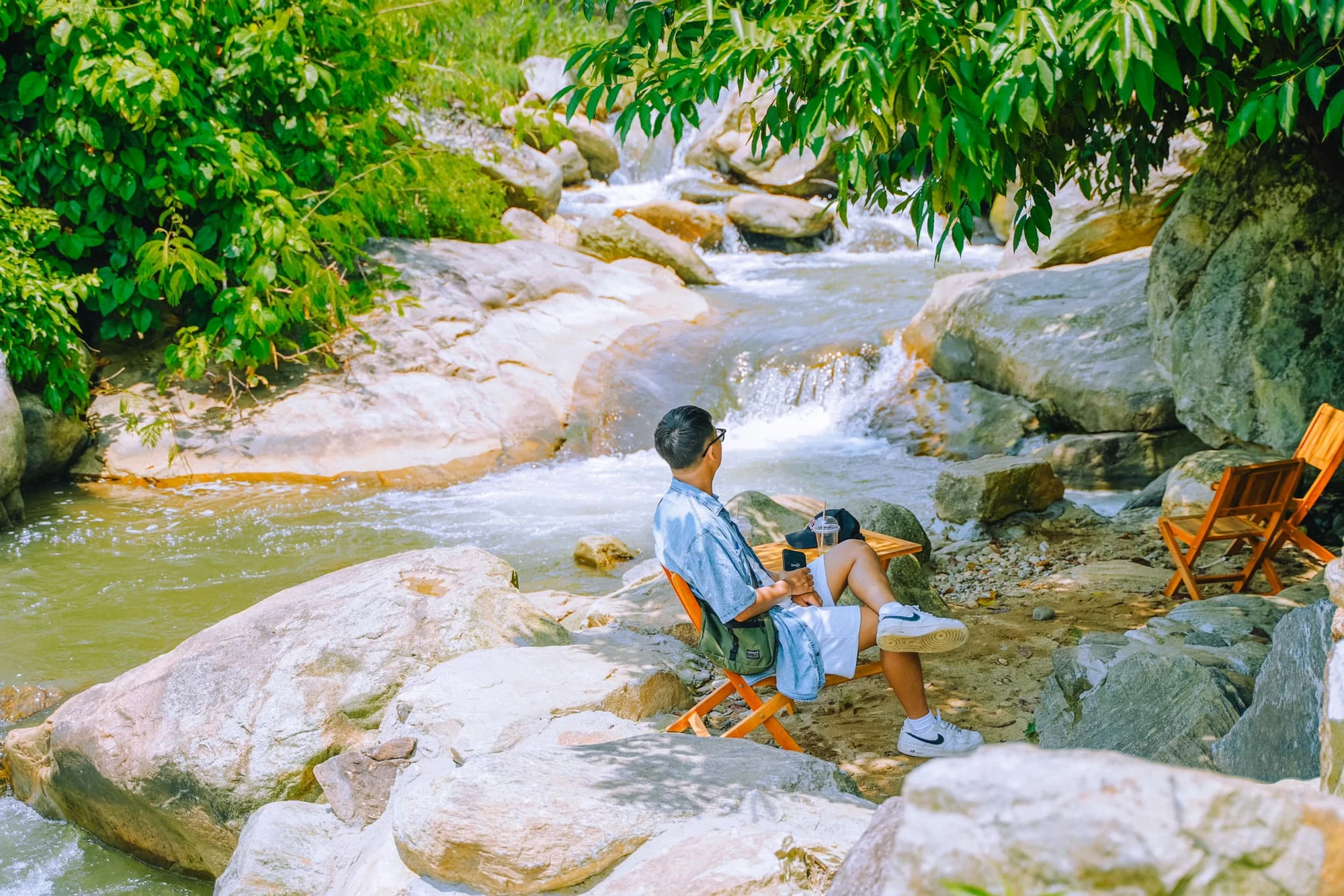 Trú dưới tán cây to lớn và hòa vào dòng suối mát lành Ảnh : NGỌC LÂM