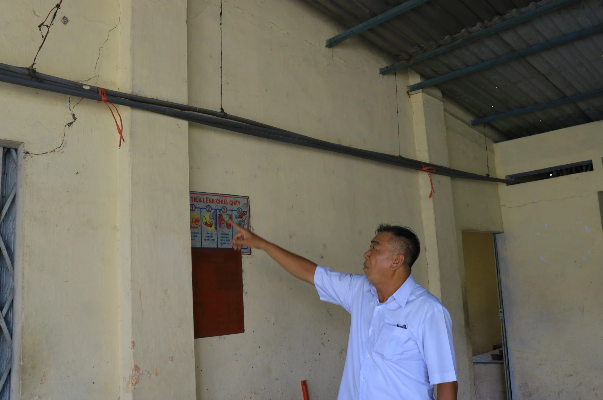 Ông Trần Văn Thanh chỉ ra những vết nứt dài trên tường trong gian bếp của Đình Tân Thới Nhất. Ảnh: VÕ THƠ