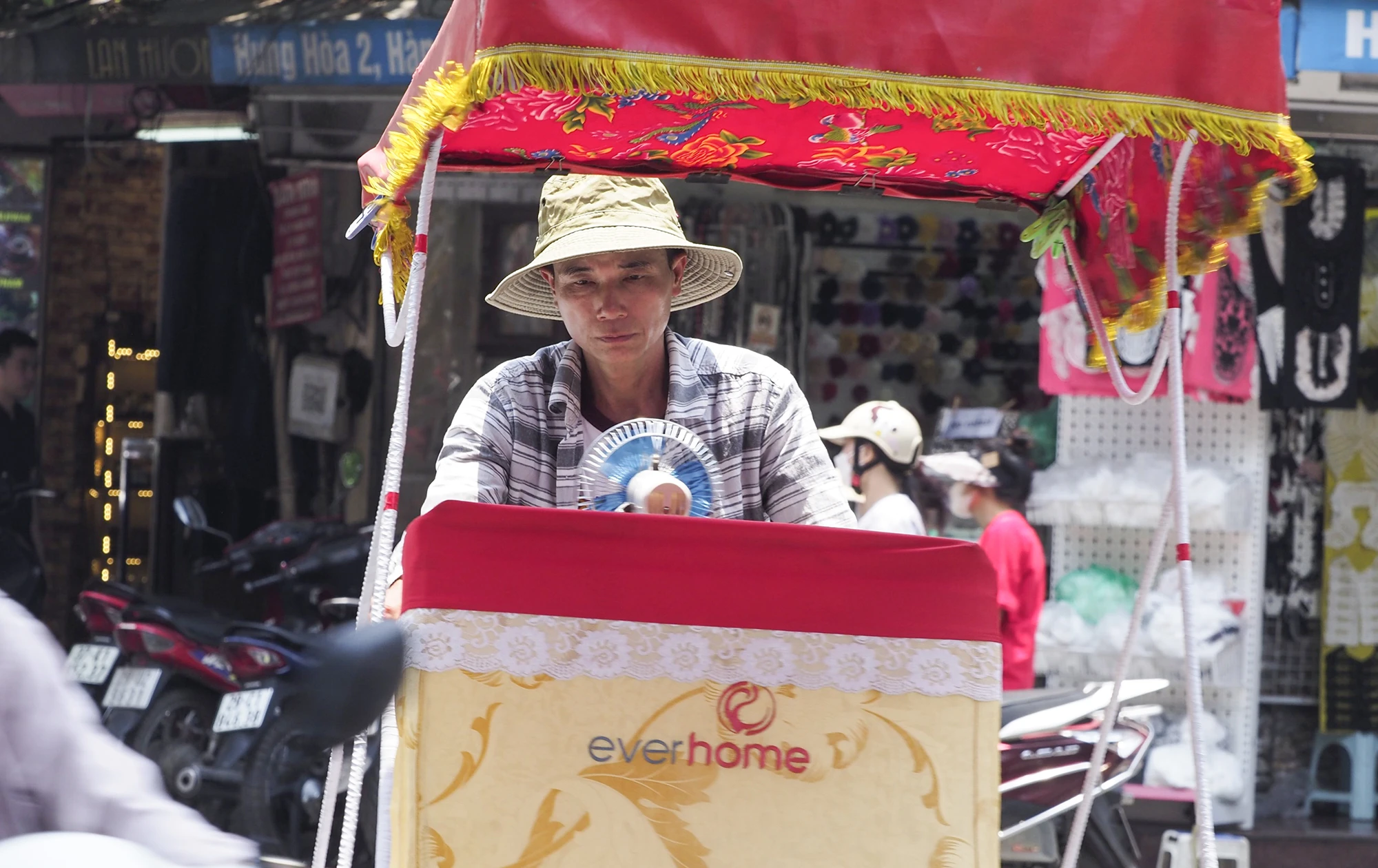 Một người đàn ông đạp xích lô gắn luôn chiếc quạt mini lên xe. Một người đàn ông đạp xích lô gắn luôn chiếc quạt mini lên xe.