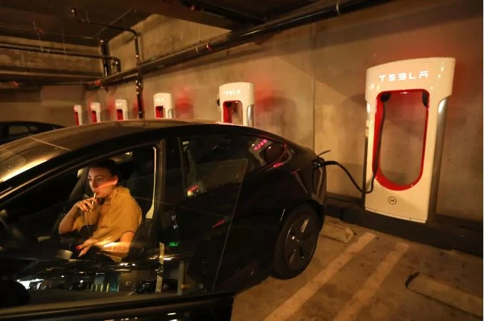 Một tài xế đang thưởng thức đồ uống trong khi chờ sạc xe điện bên trong gara tại khu chung cư Haven ở thành phố Culver (California, Mỹ).