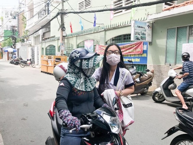 Phụ huynh TP.HCM đưa con đi thi che chắn kín mít để chống nóng. Ảnh: Phan Yên