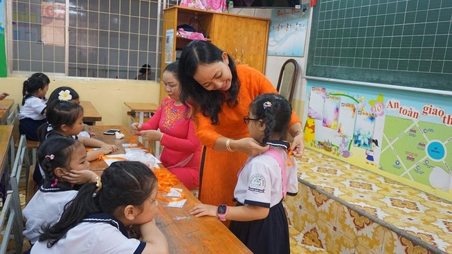 Học sinh lớp 1 trường tiểu học Trần Quốc Thảo, quận 3 được giáo viên ân cần đeo bảng tên. Ảnh: NGUYỄN QUYÊN