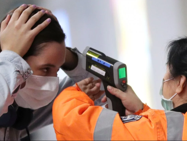 Một hành khách đến sân bay quốc tế Hong Kong đang được kiểm tra nhiệt độ. Ảnh: REUTERS