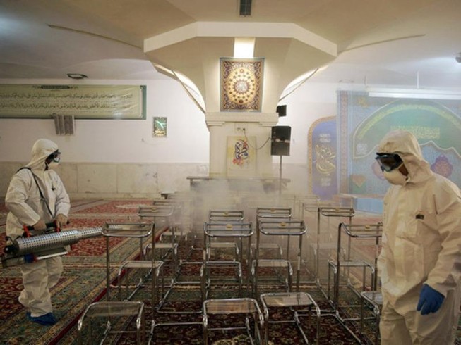 Xịt khử trùng tại một ngôi đền ở Iran - Ảnh: REUTERS