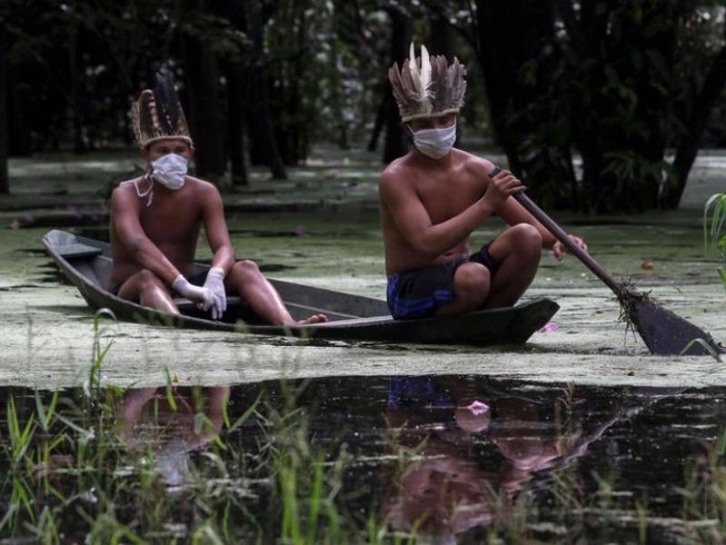 Hai người đàn ông Satere-mawe, thuộc nhóm người bản địa Brazil đang chèo thuyền trên sông Ariau, thuộc bang Amazonas (Brazil). Ảnh: AFP