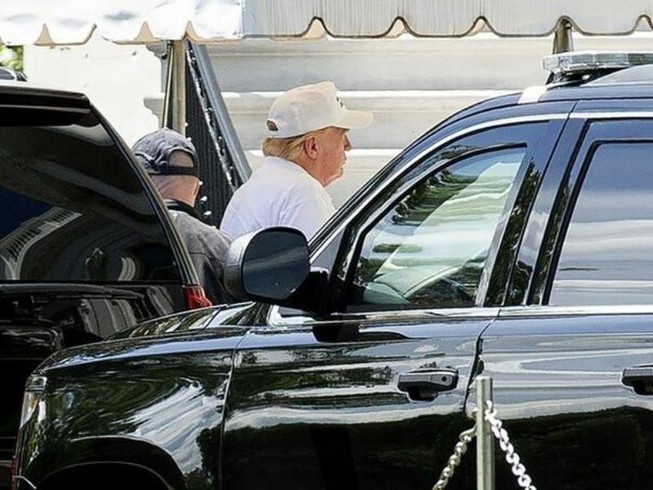 Tổng thống Trump đội mũ lưỡi trai và mặc áo phông trắng đi chơi golf. Ảnh: BLOOMBERG
