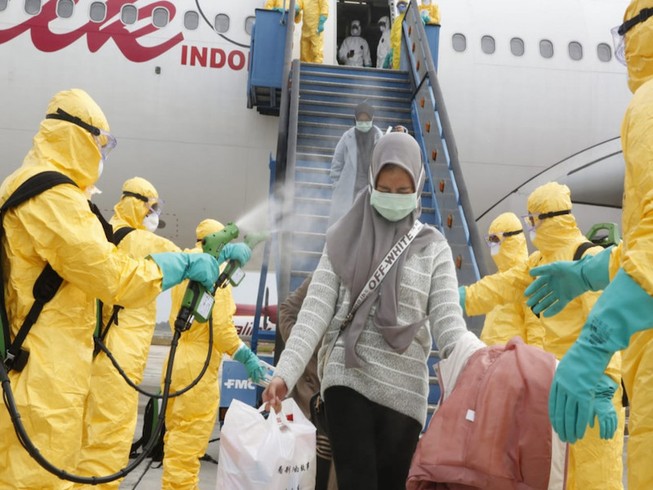 Nhân viên y tế phun thuốc khử trùng cho những người Indonesia được sơ tán khỏi Trung Quốc tại sân bay quốc tế Hang Nadim, quần đảo Riau ngày 16-2. Ảnh: BỘ NGOẠI GIAO INDONESIA