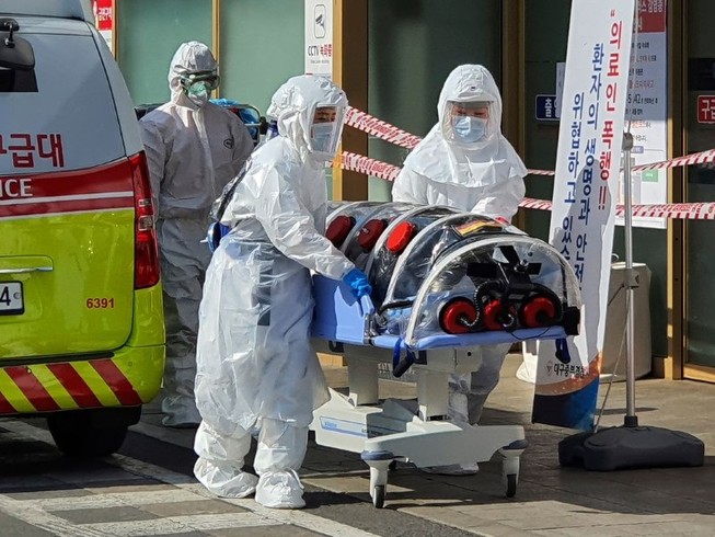 Nhân viên y tế di chuyển một người nghi nhiễm COVID-19 ở TP Daegu hôm 21-2. Ảnh: AFP