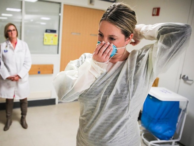 Một bác sĩ hướng dẫn cách đeo khẩu trang đúng cách tại Bệnh viện Massachusetts (Boston) ngày 27-2. Ảnh: REUTERS