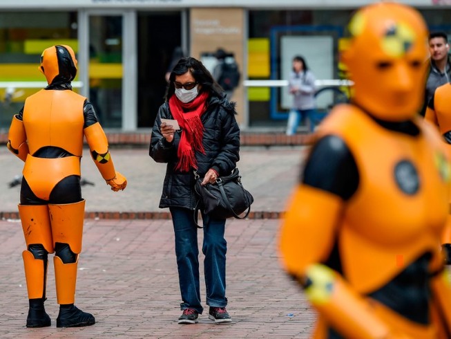 Một phụ nữ đeo khẩu trang đi bên cạnh hai robot giữ trật tự giao thông ở thủ đô Bogota, Columbia ngày 6-3. Ảnh: AFP