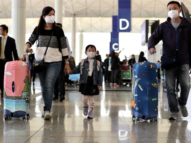 Hành khách đeo khẩu trang di chuyển vào sân bay quốc tế Hong Kong ngày 22-1. Ảnh: REUTERS