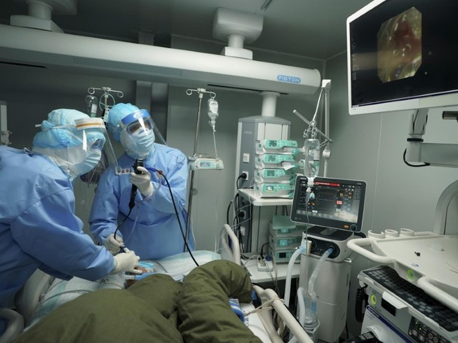 Các bác sĩ thăm khám cho người nghi nhiễm COVID-19 tại bệnh viện dã chiến Hoả Thần Sơn, Vũ Hán ngày 17-3. Ảnh: TÂN HOA XÃ