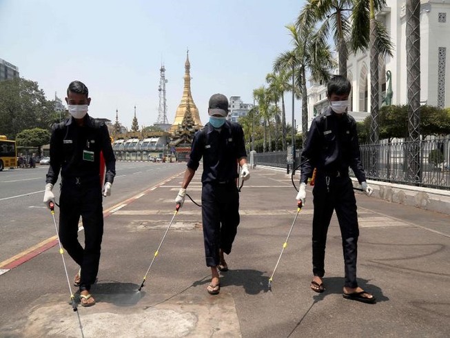 Các nhân viên khử trùng đường phố ở TP Yangon, Myanmar ngày 30-3. Ảnh: AFP