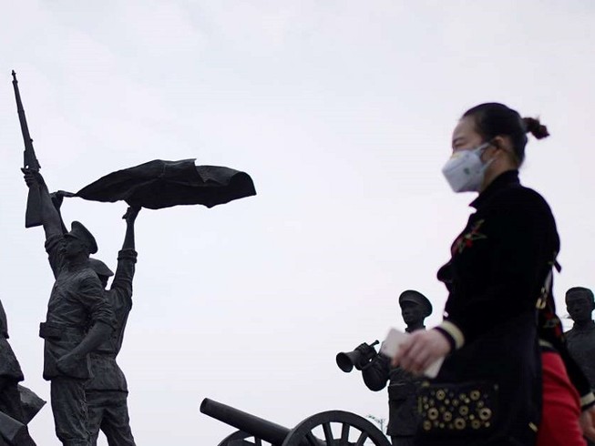 Một người phụ nữ đi ngang qua Tượng đài Cách mạng Tân Hợi ở Vũ Hán hôm 6-4. Ảnh: REUTERS