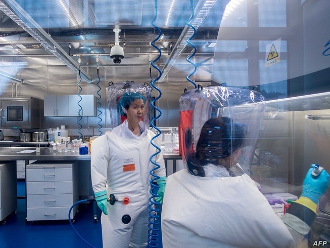 Chuyên gia virus học Thạch Chính Lệ (trái) làm việc trong phòng thí nghiệm an toàn sinh học cấp độ 4 thuộc Viện Virus học Vũ Hán hôm 23-2-2017. Ảnh: AFP