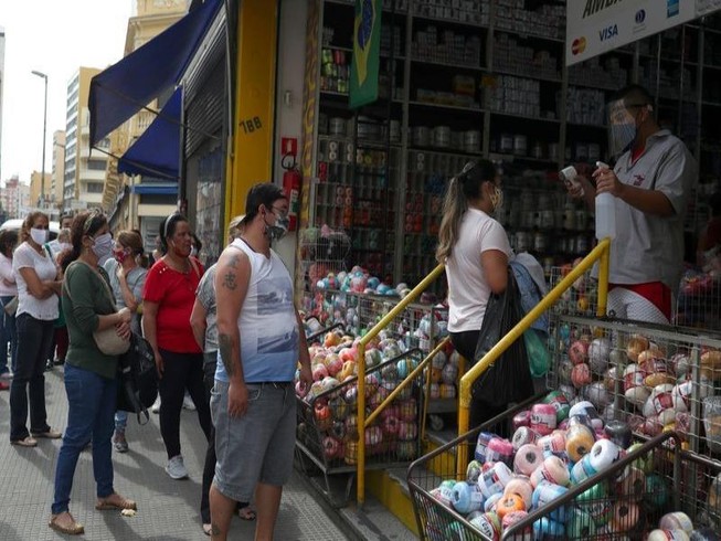 Một nhân viên kiểm tra nhiệt độ khách hàng khi đang xếp hàng để vào cửa hàng mua sắm tại Sao Paulo, Brazil, ngày 10-6-2020.