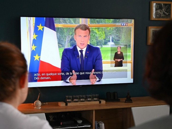 Một gia đình Pháp nghe bài phát biểu của Tổng thống Emmanuel Macron trên kênh truyền hình TFI. Ảnh: AFP