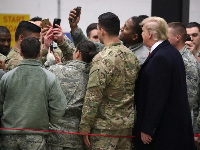 Tổng thống Mỹ Donald Trump (bên phải, áo đen) chụp hình cùng các binh sĩ Mỹ ở căn cứ Ramstein (Đức) năm 2018. Ảnh: REUTERS