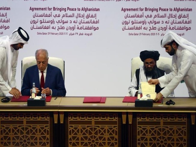 Trưởng đoàn đàm phán Taliban - ông Mullah Abdul Ghani Baradar ký thỏa thuận với đặc phái viên Mỹ về vấn đề Afghanistan MỹZalmay Khalilzad vào ngày 29-2-2020 tại Doha (Qatar). Ảnh: REUTERS/Ibraheem al Omari