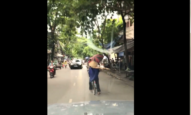 Vừa đạp xe vừa vác thang giữa nơi đông người