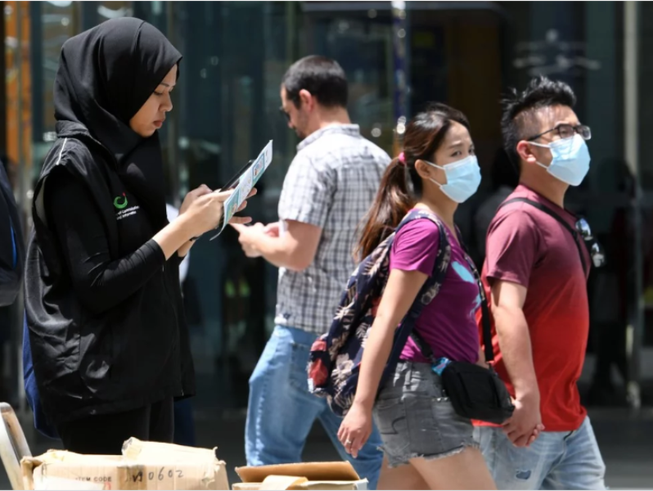 Một tình nguyện viên thuộc Bộ Truyền thông Singapore thu thập phản ánh của người dân về tình hình dịch COVID-19.