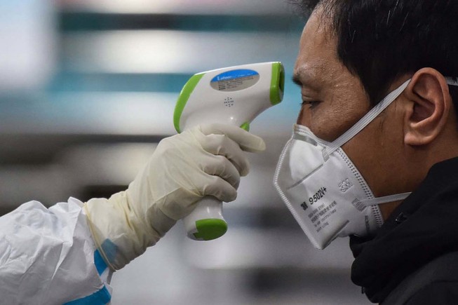 Kiểm tra thân nhiệt một bệnh nhân ở Vũ Hán. Ảnh: AFP