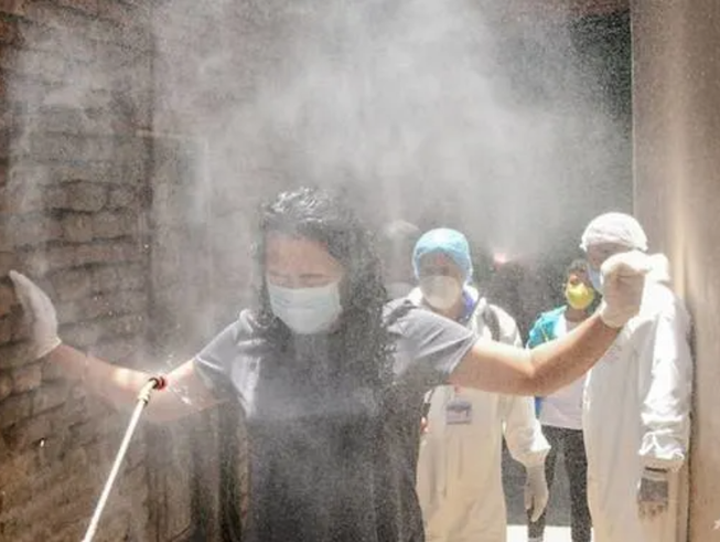 Một phụ nữ được xịt khử trùng ở Nepal. Ảnh: AFP