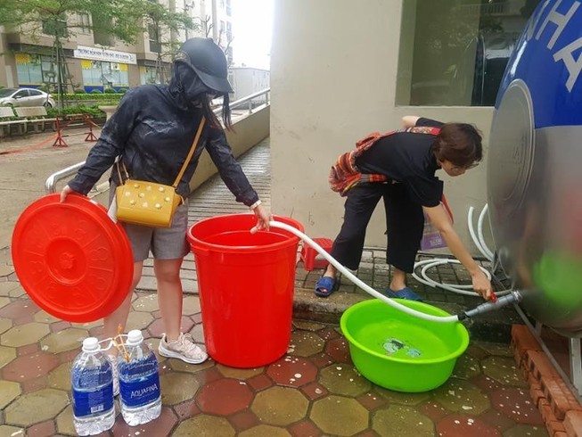 Người dân sống tại chung cư VOV (quận Nam Từ Liêm) lấy nước sạch mua từ xe téc để ăn uống, nấu cơm. Ảnh: AH