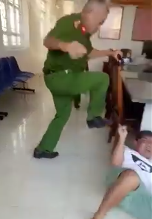 Trung tá Huỳnh Minh Lễ, Phó Công an phường Phú Thạnh, dùng chân đạp người làm chứng đang nằm trên nền trụ sở công an phường. Ảnh cắt từ clip