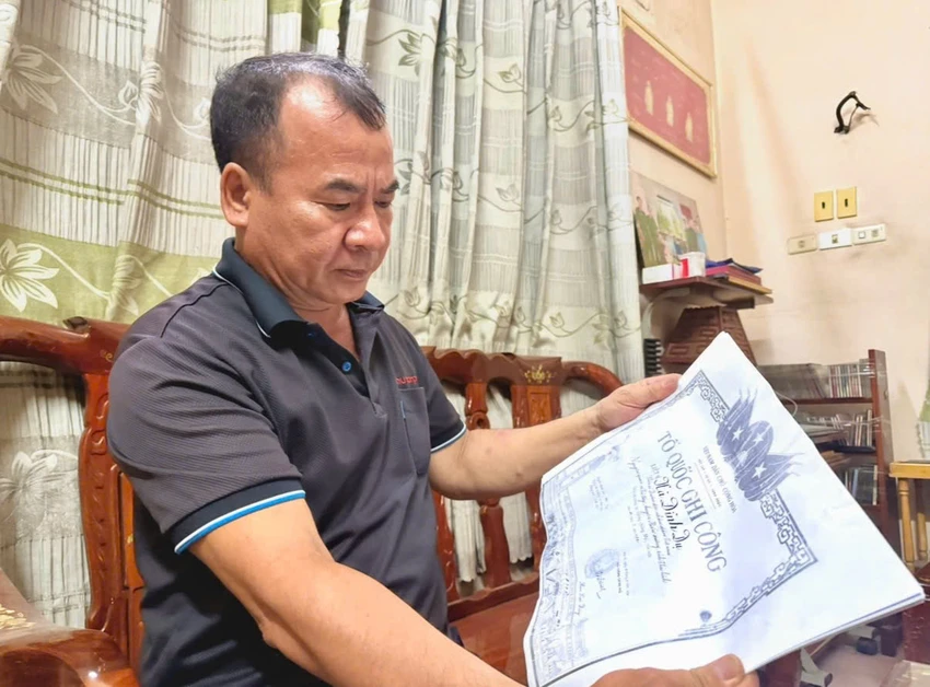 Ông Hà Minh Tuấn xem lại giấy tờ của anh mình, mong mỏi tìm được hài cốt của anh. Ảnh: HẢI NHI P13_Nguoi-co-cong_h2.jpeg