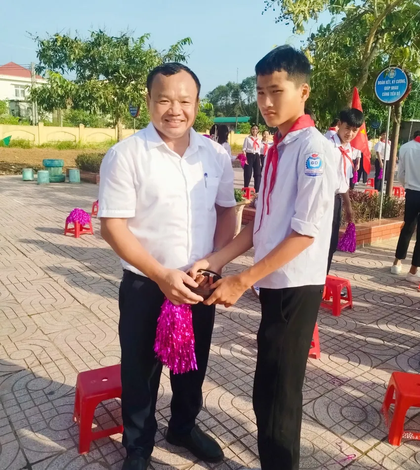 Ông Nguyễn Xuân Khánh, Phó Bí thư Thường trực Đảng ủy xã Bích Hào tháo dây thắt lưng tặng học sinh lớp 8 sau lễ khai giảng năm học mới. Ảnh: Trần Đình Thơ. hinh-anh-dep-le-khai-giang.jpg