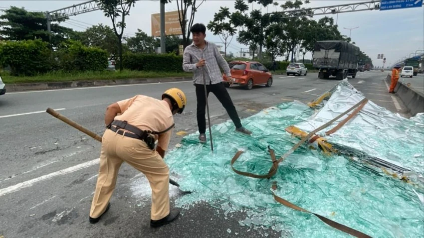 Cán bộ Đội CSGT Rạch Chiếc hỗ trợ người dân dọn dẹp mảnh kính vỡ. Ảnh: CTV kinh-vo.jpg
