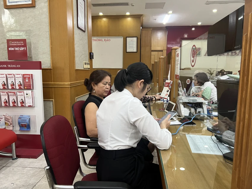 Nhân viên ngân hàng Agribank hướng dẫn khách cập nhật sinh trắc học - Ảnh: ND 1.jpg