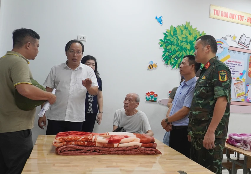 Lãnh đạo quận Hoàng Mai và phường Tân Mai sắp xếp bố trí người dân đến tránh bão ở nơi kiên cố, an toàn. Ảnh: TP Quận Hoàng Mai di chuyển hộ dân đến noi an toàn tránh bão số 3