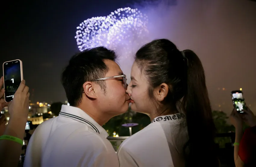 Anh Minh và chị Lan (Hoàn Kiếm, Hà Nội) đặt bàn từ trước nhiều ngày tại một quán bar nhìn xuống Hồ Gươm để có vị trí trên cao xem pháo hoa. Anh chị trao nhau nụ hôn mừng Tết độc lập. Ảnh: HOÀNG GIANG HoGuom4.jpg