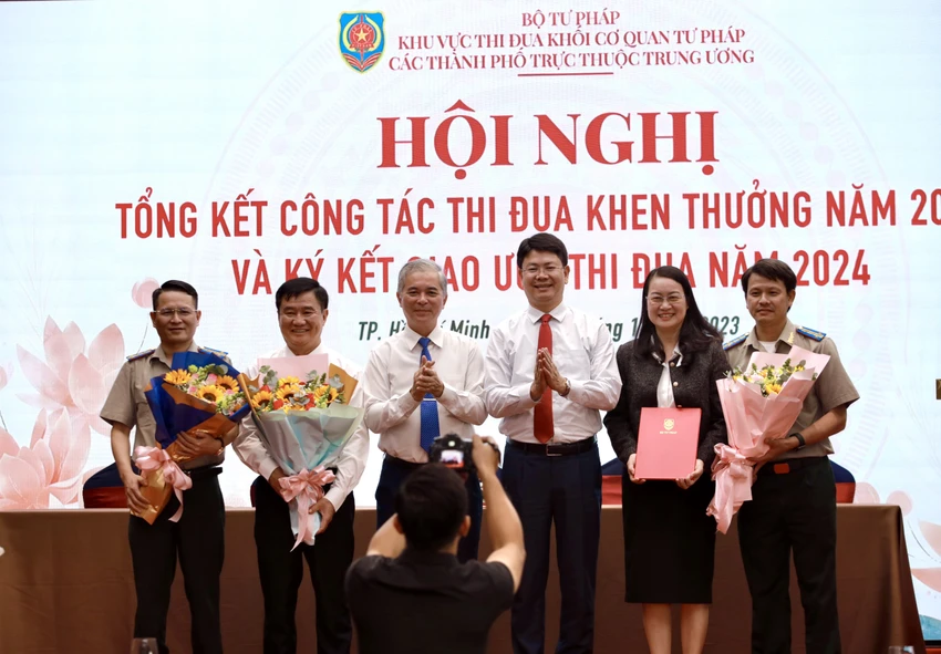 Thứ trưởng Bộ Tư pháp Nguyễn Thanh Tịnh (thứ ba từ phải qua) và PCT UBND TP.HCM Ngô Minh Châu (thứ ba từ trái qua) trao hoa chúc mừng Trưởng và Phó khu vực thi đua năm 2023 đã hoàn thành xuất sắc nhiệm vụ. Ảnh: NGUYỆT NHI thu-truong-tang-bang-khen-cho-so-tu-phap-tphcm.jpg
