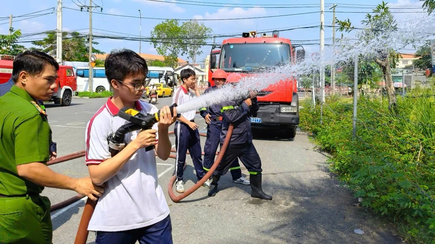 Cảnh sát PCCC&CNCH hướng dẫn các em học sinh cách thức sử dụng vòi phun nước. Ảnh: CA Quận Bình Tân đưa vào hoạt động Trung tâm giáo dục cộng đồng về PCCC&CNCH