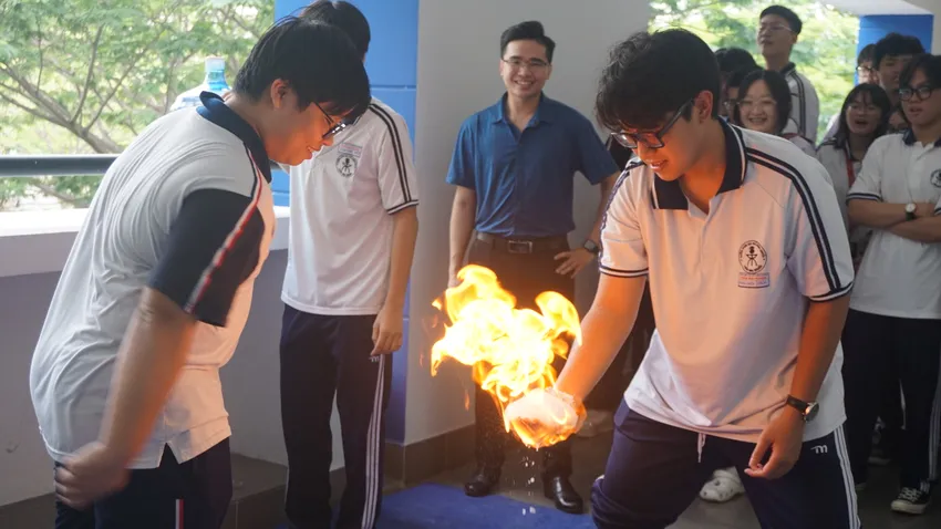 Tân học sinh khối 10 thích thú với thí nghiệm "Bàn tay lửa" do các anh chị lớp chuyên Hóa hướng dẫn và thực hiện. Ảnh: NQ Trường THPT chuyên Trần Đại Nghĩa