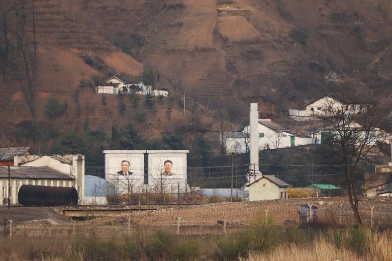 Bức chân dung khổng lồ của cố lãnh đạo Triều Tiên Kim Nhật Thành và Kim Jong-il tại một ngôi làng Triều Tiên chụp từ Đan Đông, tỉnh Liêu Ninh, Trung Quốc. Ảnh: Tingshu Wang/REUTERS