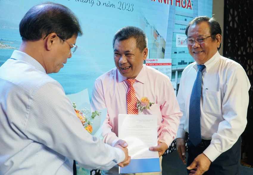 Ông Nguyễn Tấn Tuân, Chủ tịch UBND tỉnh Khánh Hòa và Tổng biên tập Mai Ngọc Phước, trao quyết định và tặng hoa chúc mừng nhà báo Lê Tấn Lộc (giữa). Ảnh: NHẬT DIỄM Ông Nguyễn Tấn Tuân tặng hoa chúc mừng nhà báo Lê Tấn Lộc (ở giữa)
